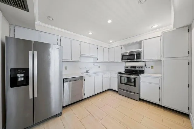 a kitchen with white cabinets and stainless steel appliances