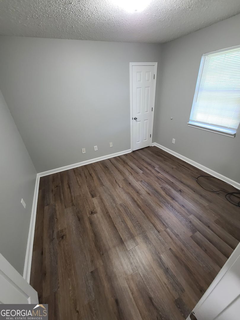 708 Green Street, Unit B Fort Valley, GA 31030 - Photo 11 of 12 an empty room with wooden floor and windows