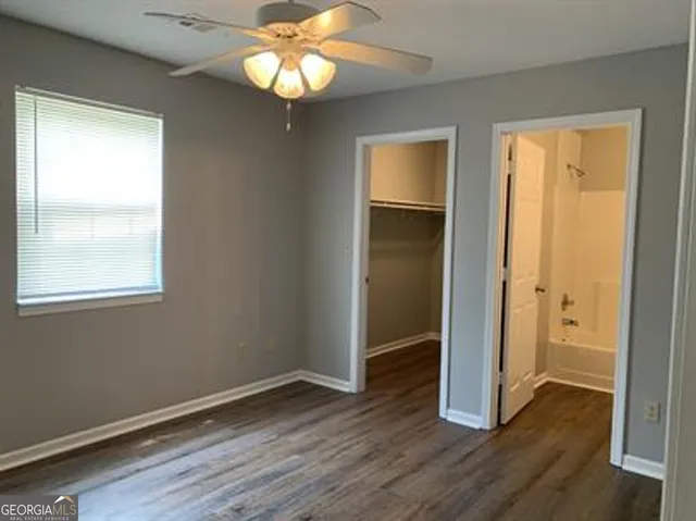 an empty room with wooden floor closet and windows