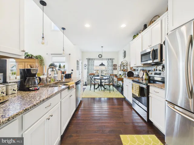 a large kitchen with stainless steel appliances granite countertop lots of counter top space a refrigerator a stove a sink and a cabinets