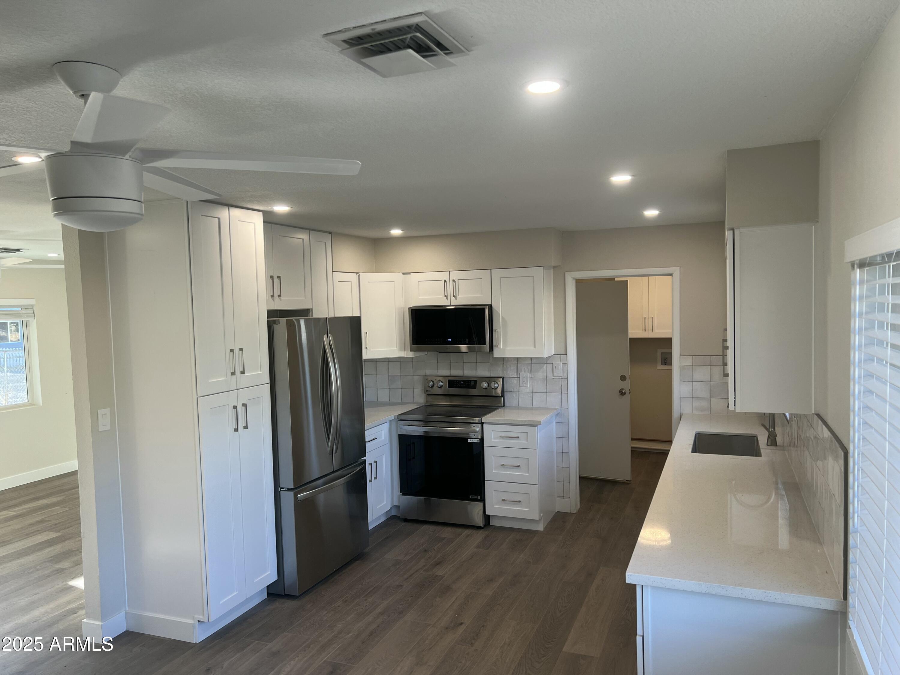 731 Elm Lane Eagar, AZ 85925 - Photo 7 of 26 a kitchen with stainless steel appliances granite countertop a refrigerator a sink a stove and a refrigerator with wooden floor
