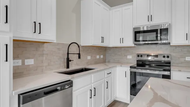 a kitchen with granite countertop a sink stove and refrigerator