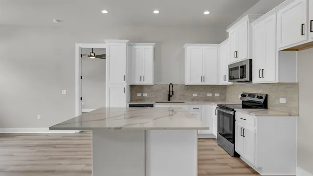 an empty room with wooden floor a ceiling fan and windows