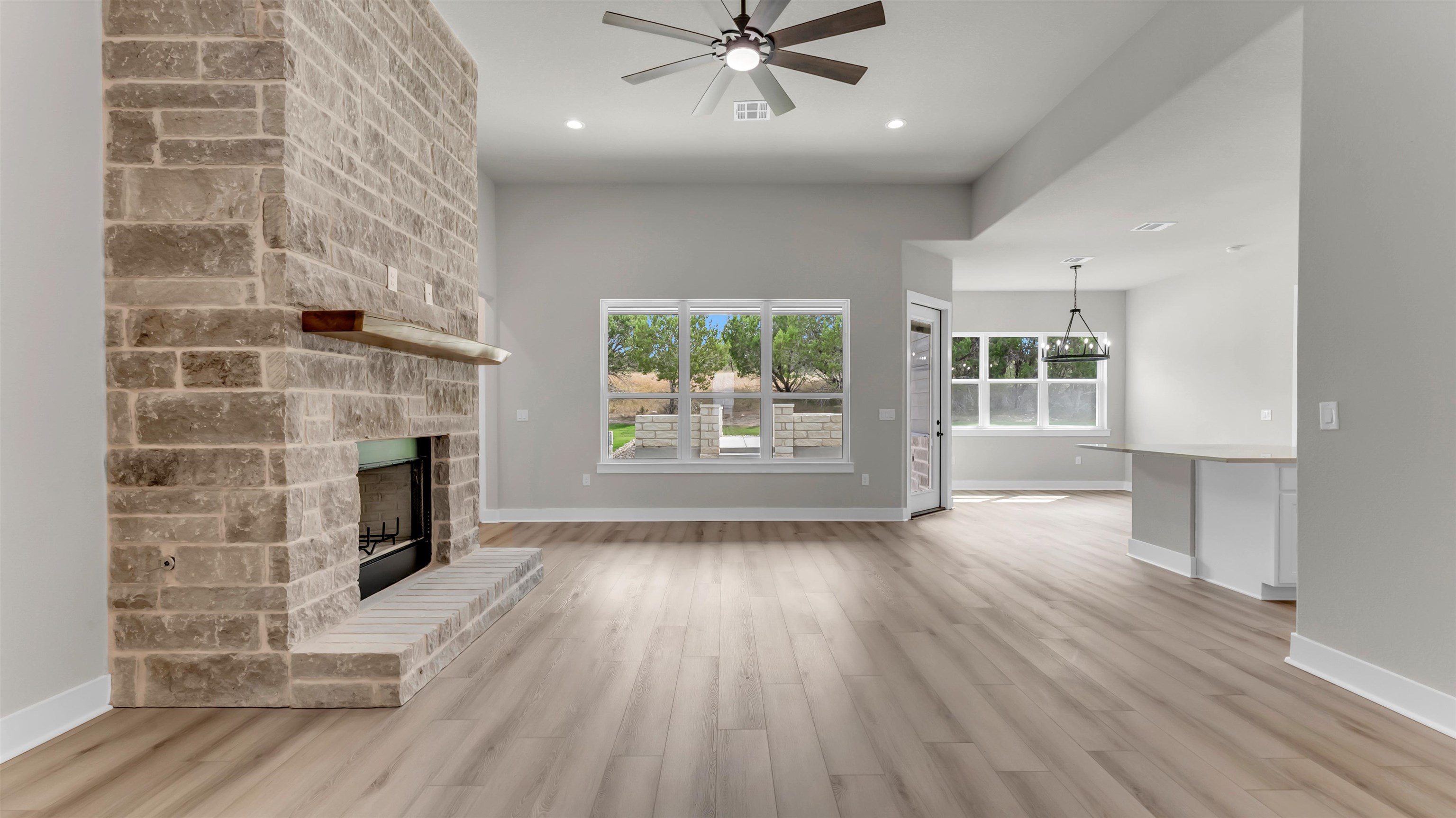 119 Garner Rnch Road Bertram, TX 78605 - Photo 10 of 25 an empty room with windows fireplace and wooden floor