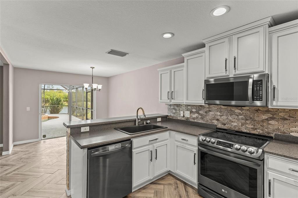 11754 Tempest Harbor Loop Venice, FL 34292 - Photo 9 of 56 a kitchen with stainless steel appliances granite countertop a sink stove and microwave