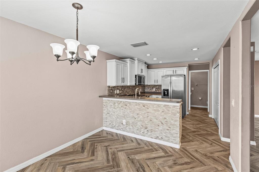 11754 Tempest Harbor Loop Venice, FL 34292 - Photo 10 of 56 a large kitchen with kitchen island white cabinets and chandelier