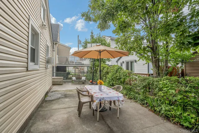 a view of a patio with a table and chairs under an umbrella with a small yard