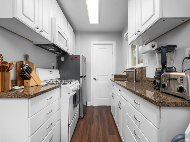 225 South 300 East Provo, UT 84606 - Photo 6 of 30 Galley-style kitchen featuring white cabinetry, brown granite-finish countertops, wood-finish flooring, a stainless steel sink with a high-arc faucet, and an integrated microwave