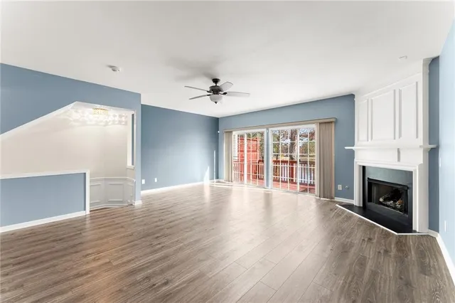 a view of an empty room with wooden floor fireplace and a window