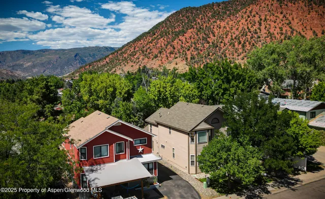 a aerial view of a house with yard and trees in the background