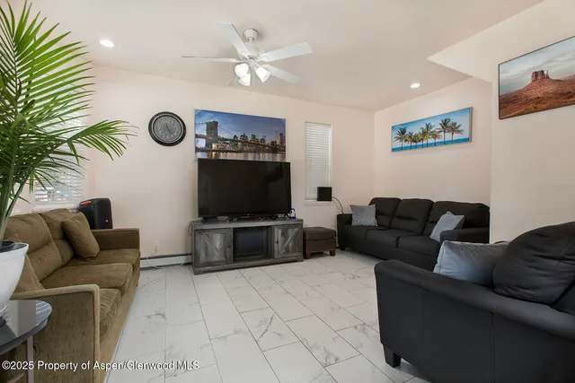 a living room with furniture a flat screen tv and a wall painting