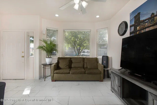 a living room with furniture a flat screen tv and a large window