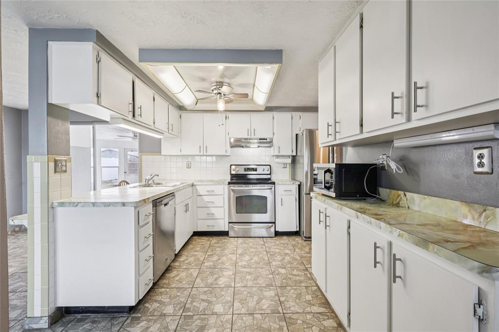 3548 Darlington Road Holiday, FL 34691 - Photo 12 of 32 a kitchen with stainless steel appliances granite countertop a stove sink and cabinets