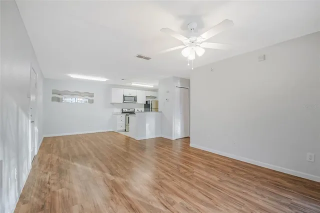 a view of a kitchen with wooden floor and a ceiling fan