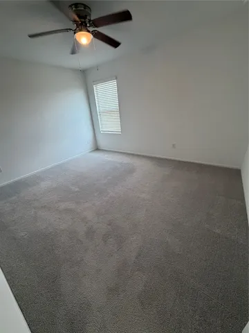 an empty room with a chandelier fan and windows