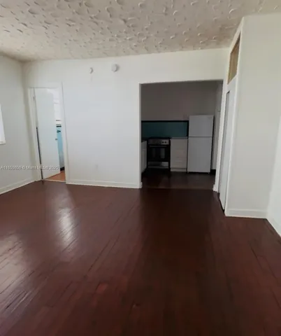 an empty room with wooden floor fireplace and a window