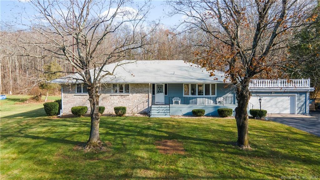 a view of a house with a big yard and large tree