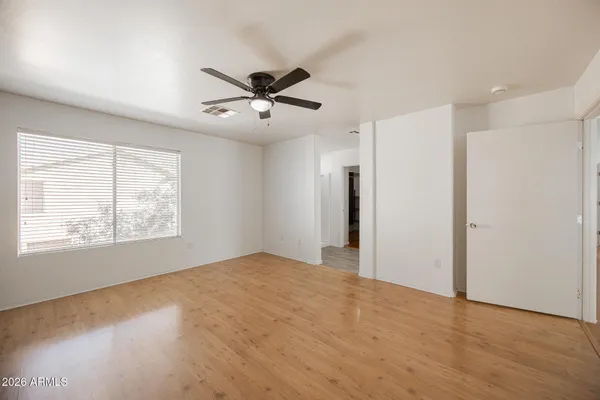 a view of empty room with wooden floor and fan