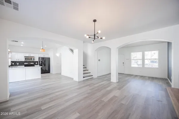 a view of an empty room with kitchen and window