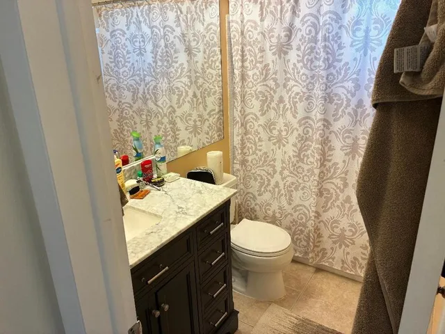 a bathroom with a granite countertop sink and a toilet