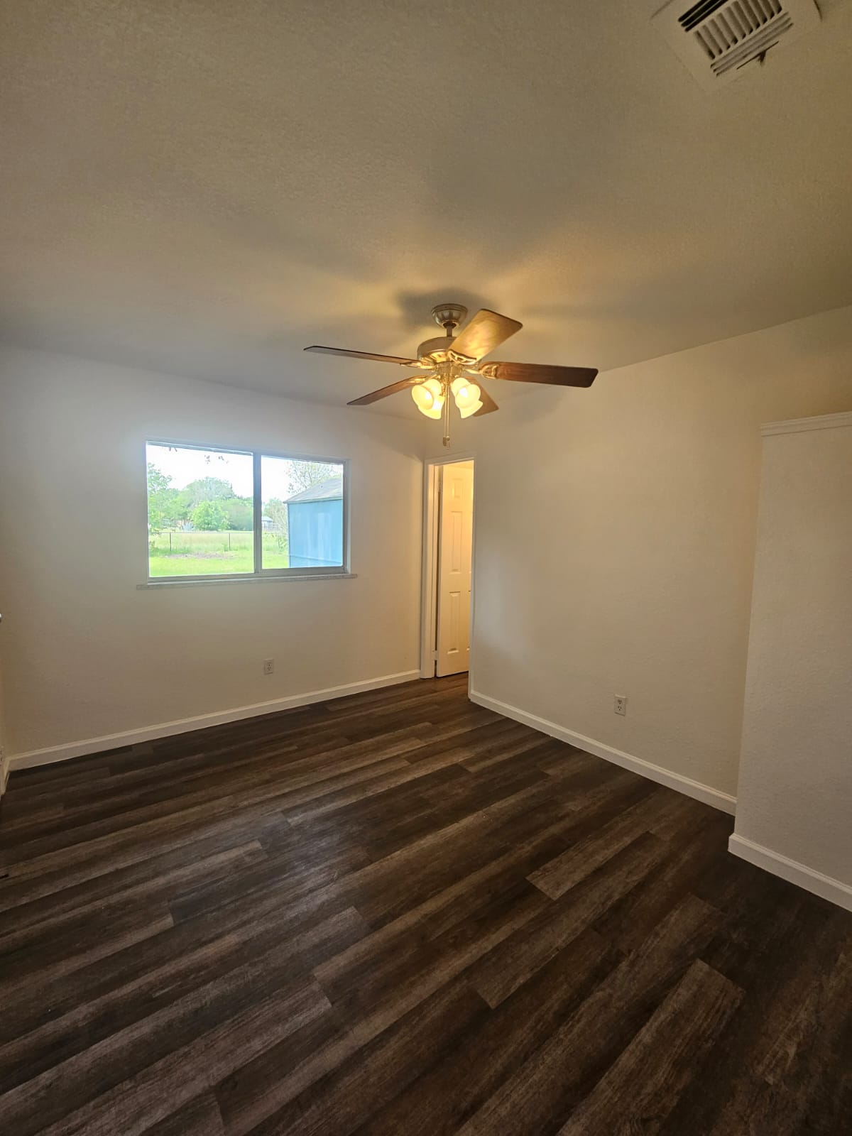 1401 Trinity Street Lockhart, TX 78644 - Photo 14 of 31 Bedroom featuring wood-finish flooring, white baseboards, a ceiling fan with integrated lighting, and a window providing exterior light