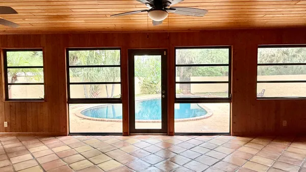 a view of an empty room with window and a chandelier fan