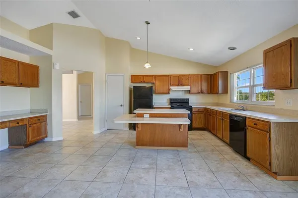 a large kitchen with stainless steel appliances kitchen island granite countertop a stove a sink a counter top space and cabinets