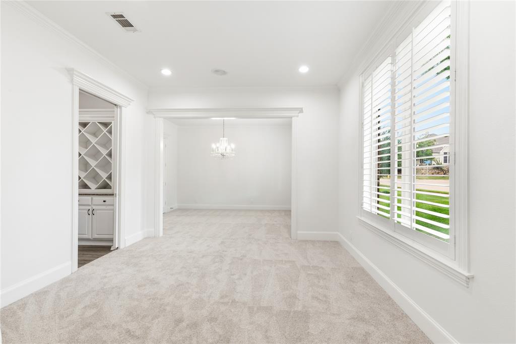 967 East Bethel School Road Coppell, TX 75019 - Photo 10 of 39 Carpeted interior space with a window featuring white plantation shutters and an adjacent room with a built-in wine rack and lower cabinetry