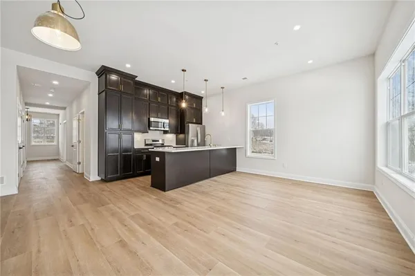 a large white kitchen with kitchen island a sink wooden floor and a refrigerator