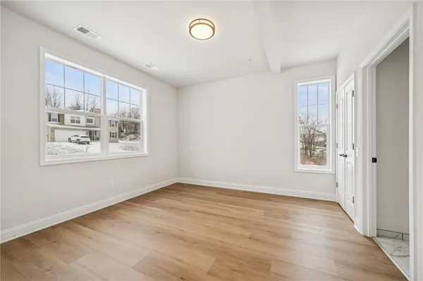 an empty room with wooden floor and window