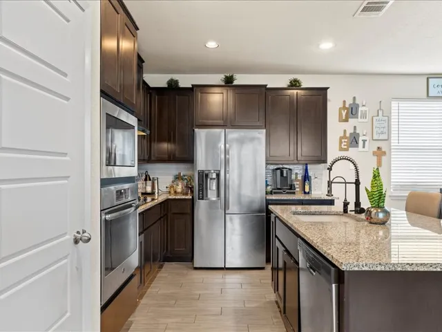 a kitchen with granite countertop stainless steel appliances cabinets a sink and a counter top space