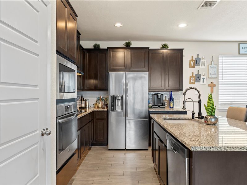 204 Lake Placid Run Elgin, TX 78621 - Photo 9 of 19 a kitchen with granite countertop stainless steel appliances cabinets a sink and a counter top space