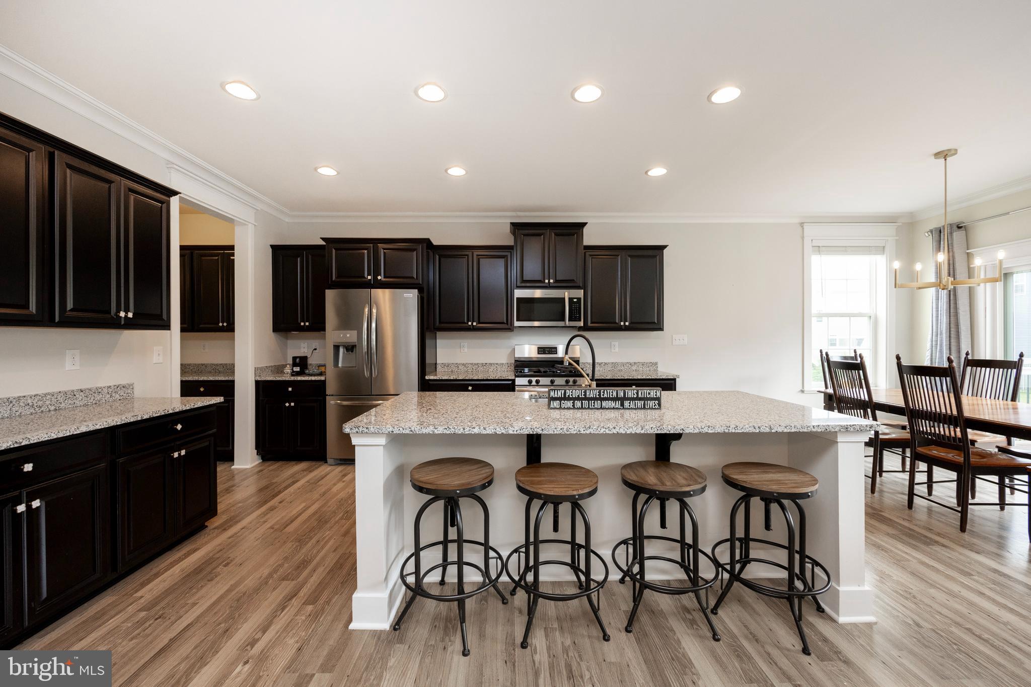 45 Nichols Mill Road Downingtown, PA 19335 - Photo 11 of 47 a kitchen with stainless steel appliances kitchen island granite countertop a dining table chairs refrigerator and microwave