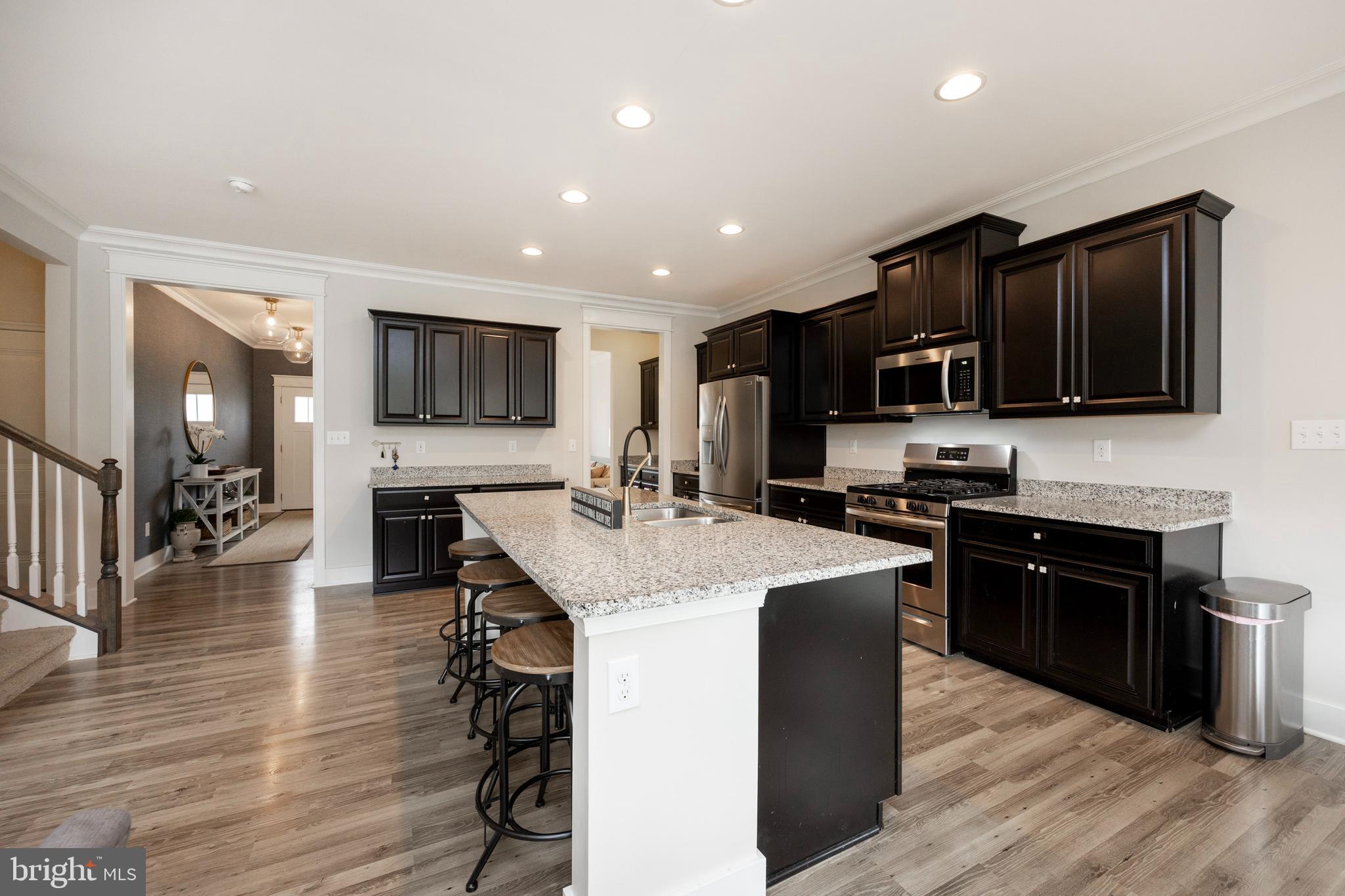 45 Nichols Mill Road Downingtown, PA 19335 - Photo 10 of 47 a kitchen with stainless steel appliances granite countertop a stove top oven a sink dishwasher a refrigerator and a dining table with wooden floor