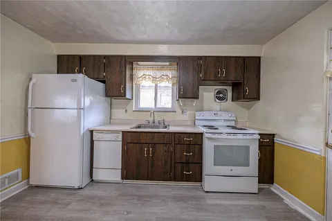 a kitchen with a sink a refrigerator and a stove top oven
