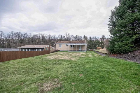 a view of a house with a yard and a large tree