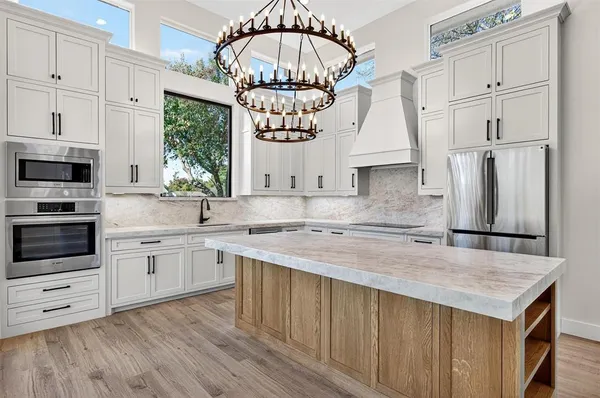 a kitchen with stainless steel appliances a stove a sink dishwasher a refrigerator and a oven with wooden floor