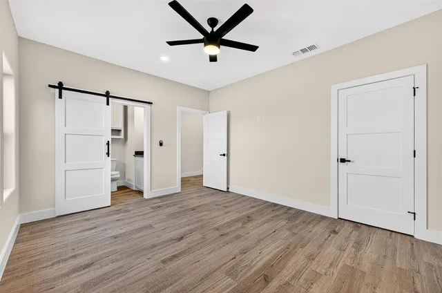 an empty room with wooden floor and a ceiling fan