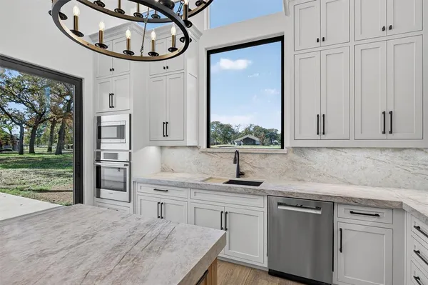 a kitchen with kitchen island granite countertop a sink a stove and cabinets