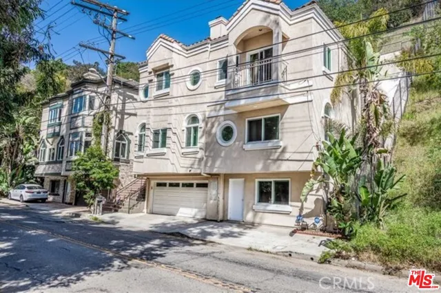 a view of a white building among the street with palm trees
