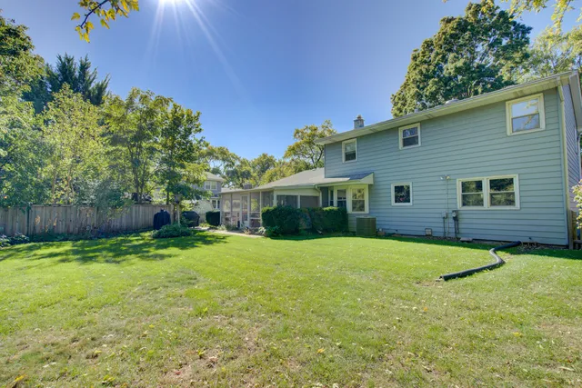 a backyard of a house with plants and large tree