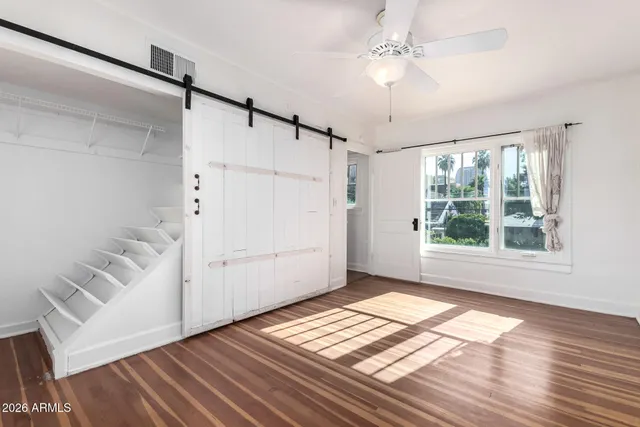 a view of an empty room with a window and wooden floor