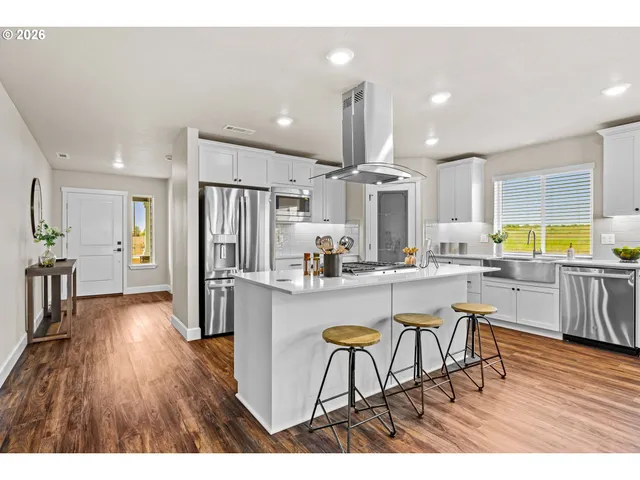 a kitchen with stainless steel appliances a dining table chairs refrigerator and sink