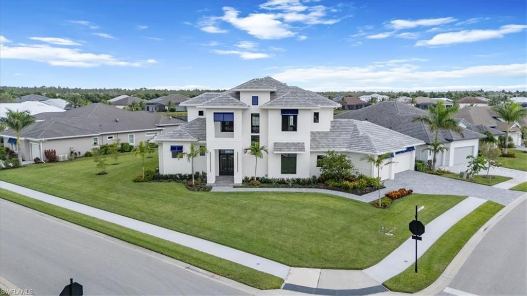 View of front of home featuring stucco siding, an attached garage, decorative driveway, a front yard, and a residential view