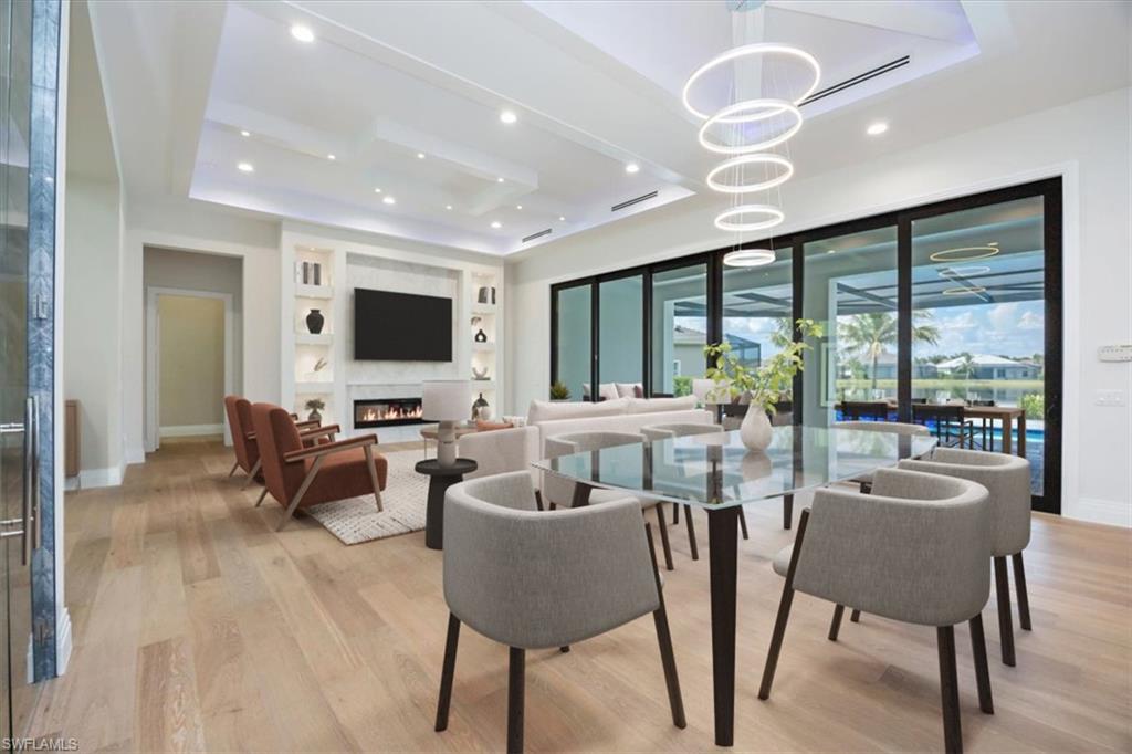 14211 Charthouse Circle Naples, FL 34114 - Photo 2 of 48 Dining area with a tray ceiling, light wood finished floors, a fireplace, recessed lighting, and built in features