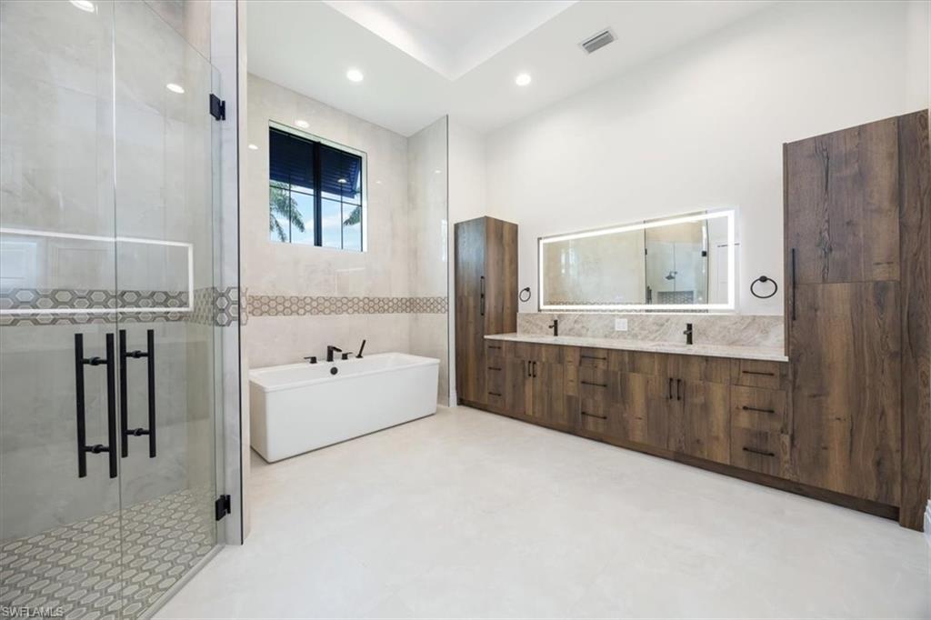 14211 Charthouse Circle Naples, FL 34114 - Photo 21 of 48 Bathroom with a soaking tub, a shower stall, double vanity, tile walls, and recessed lighting