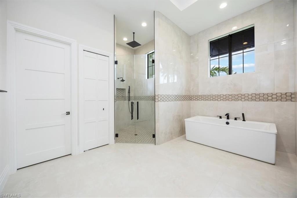 14211 Charthouse Circle Naples, FL 34114 - Photo 22 of 48 Full bathroom featuring tile walls, a shower stall, a freestanding bath, and recessed lighting