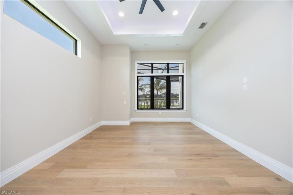 14211 Charthouse Circle Naples, FL 34114 - Photo 24 of 48 Spare room featuring a tray ceiling, light wood finished floors, ceiling fan, and recessed lighting