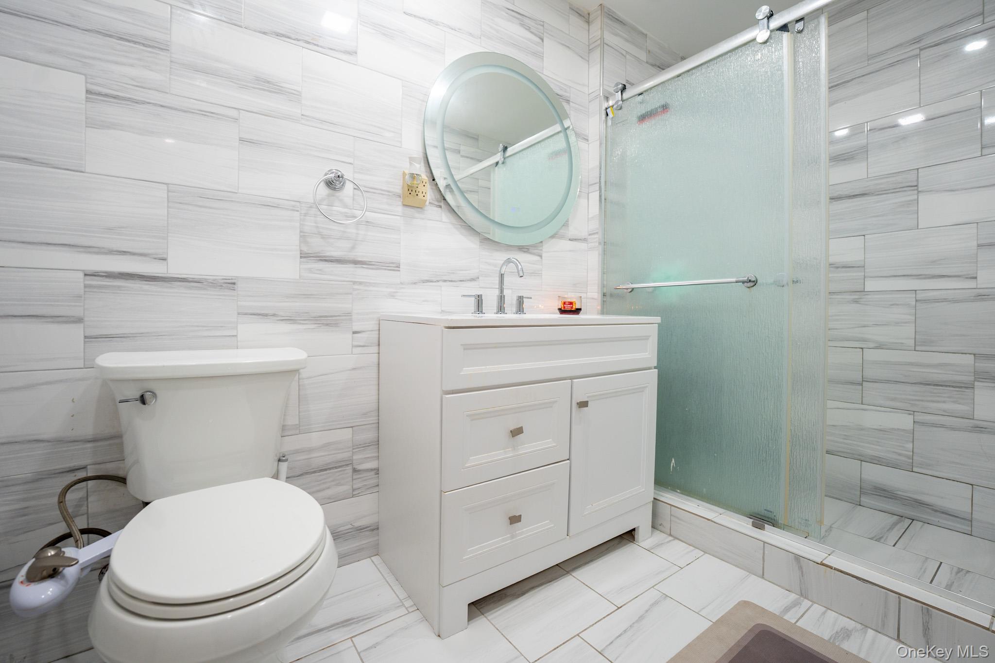 23 Yucca Drive Staten Island, NY 10312 - Photo 13 of 21 Full bath featuring vanity, a stall shower, and tile walls