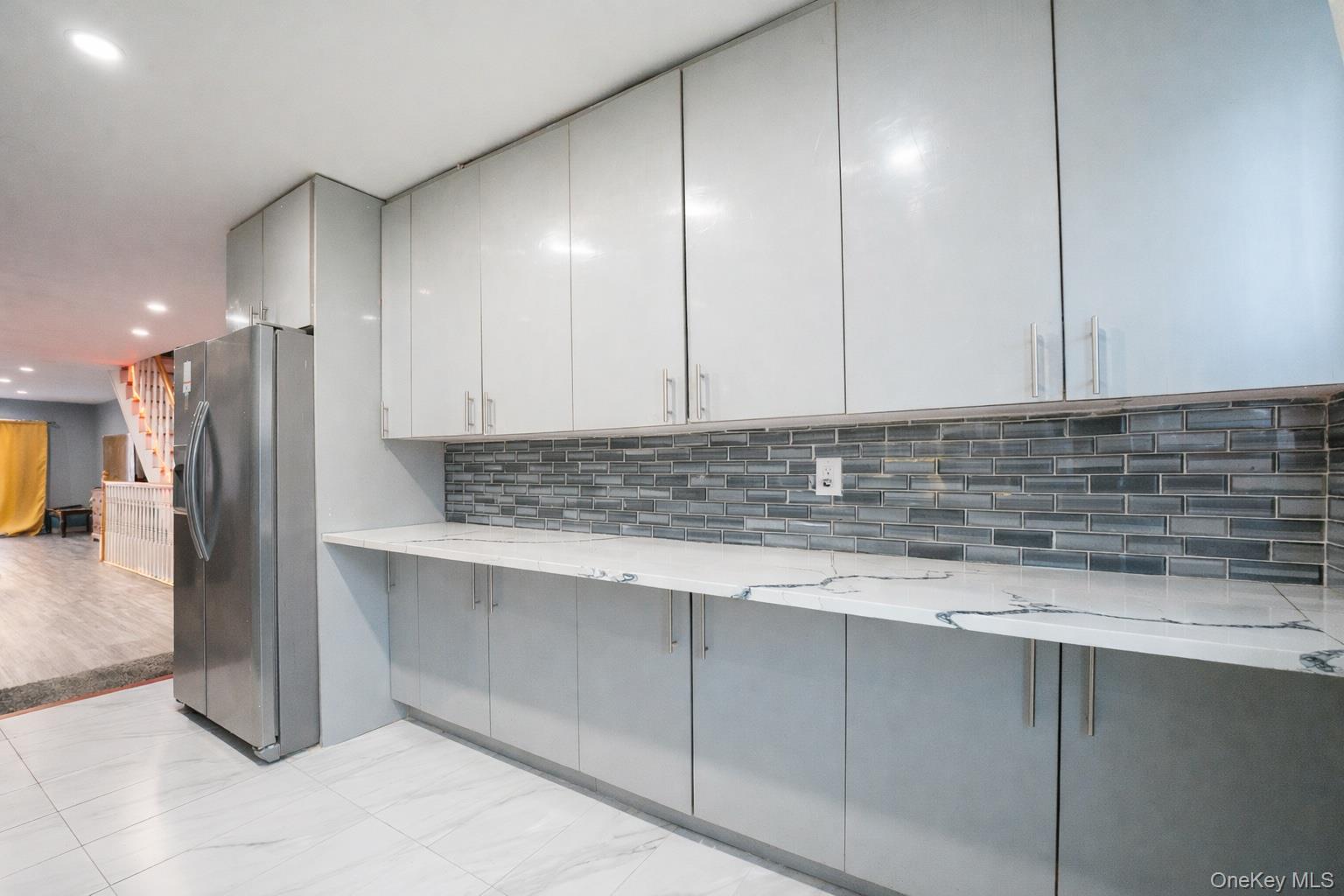 23 Yucca Drive Staten Island, NY 10312 - Photo 15 of 21 Kitchen featuring gray cabinets, stainless steel fridge with ice dispenser, modern cabinets, recessed lighting, and light stone counters